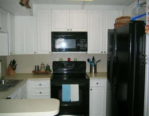 8231 B Thames Boulevard, Unit B Boca Raton, FL 33433 - Photo 5 of 10 a kitchen with a refrigerator and white cabinets