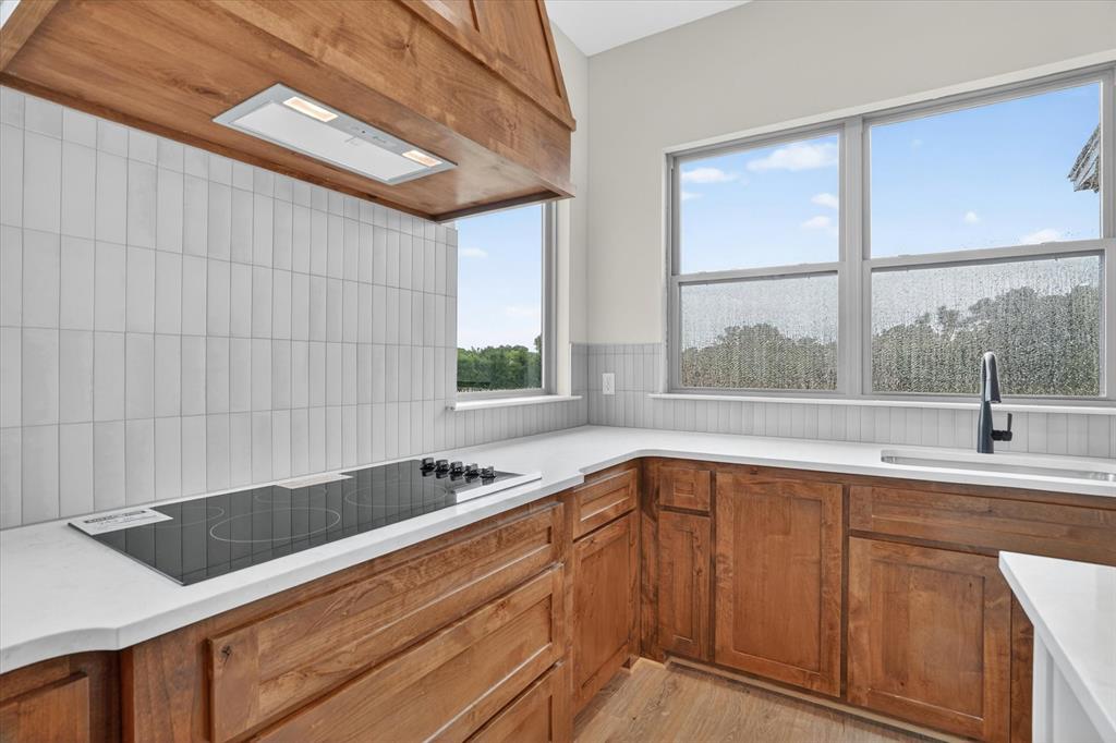 225 Kilkenny Road Poolville, TX 76487 - Photo 14 of 36 Kitchen featuring wood cabinetry, white countertops, a built-in cooktop, and a white tile backsplash