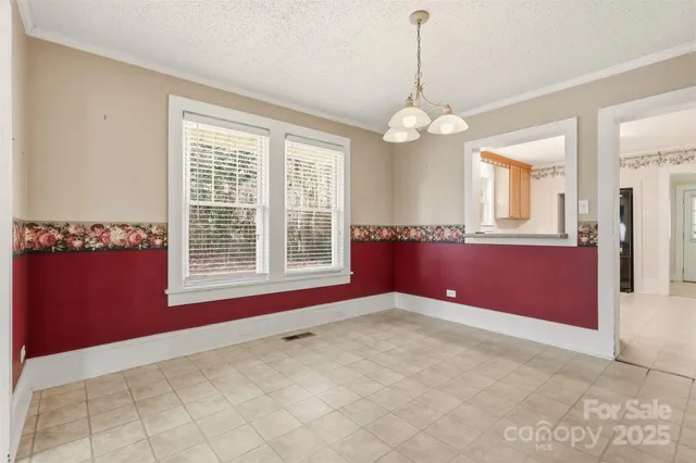 a view of an empty room with a window and a kitchen
