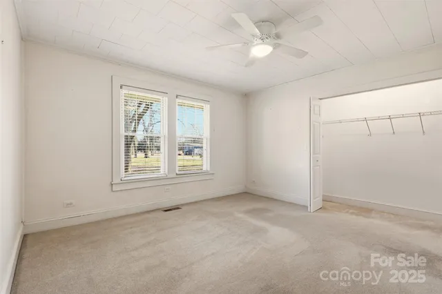 an empty room with windows and fan