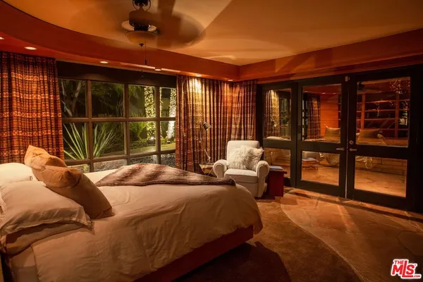 a bed sitting in a spacious bedroom next to a large window