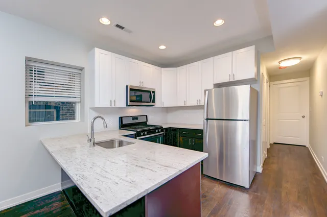 a kitchen with stainless steel appliances granite countertop a refrigerator a sink a stove a microwave a counter space and wooden floor