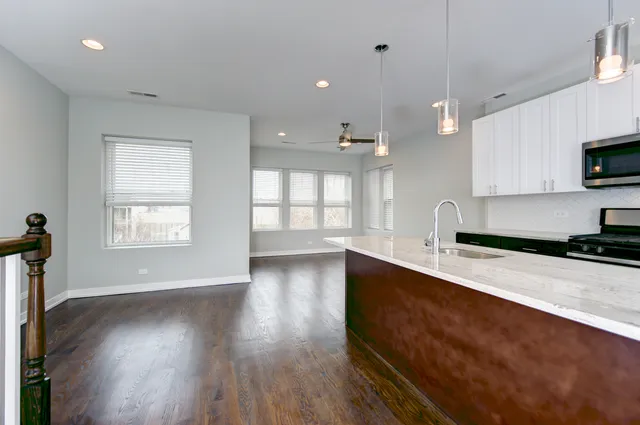 a large kitchen with stainless steel appliances a large counter top a stove a sink and a window