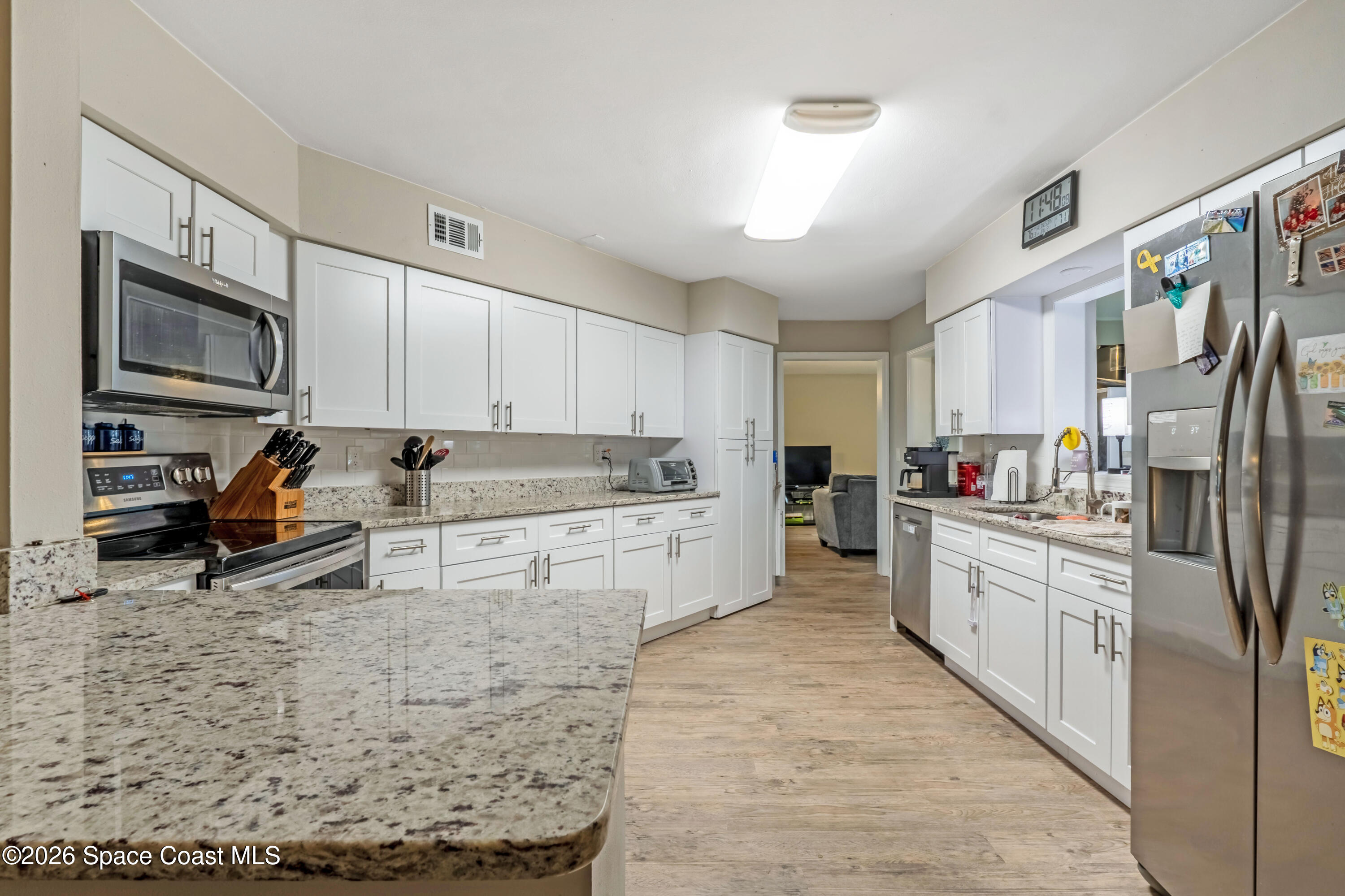 220 Alhambra Street Titusville, FL 32780 - Photo 22 of 29 a kitchen with stainless steel appliances granite countertop a stove top oven a refrigerator a sink and dishwasher with white cabinets