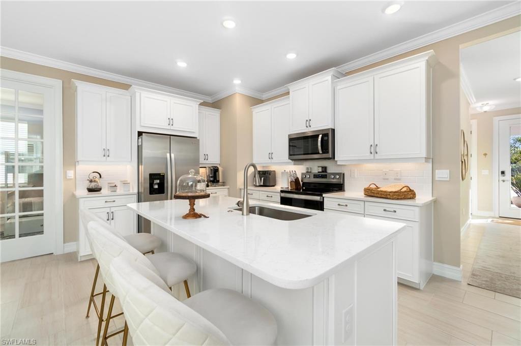 28298 Captiva Shell Loop Bonita Springs, FL 34135 - Photo 15 of 49 a kitchen with white cabinets and stainless steel appliances