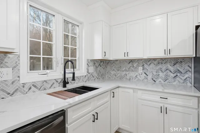 a kitchen with granite countertop white cabinets and stainless steel appliances