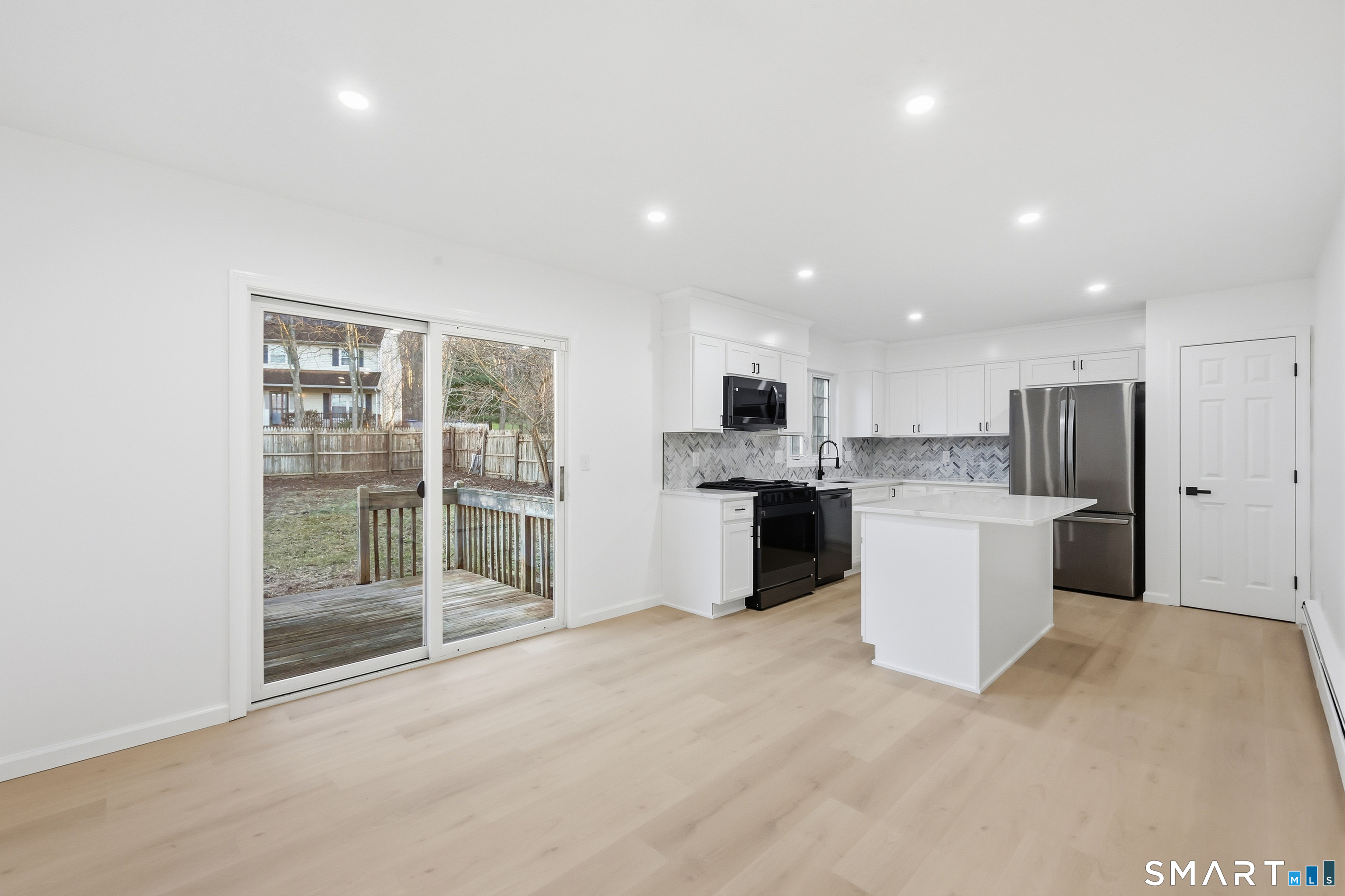 70 Victoria Court Hamden, CT 06514 - Photo 6 of 30 a large white kitchen with a refrigerator a sink dishwasher and white cabinets with wooden floor