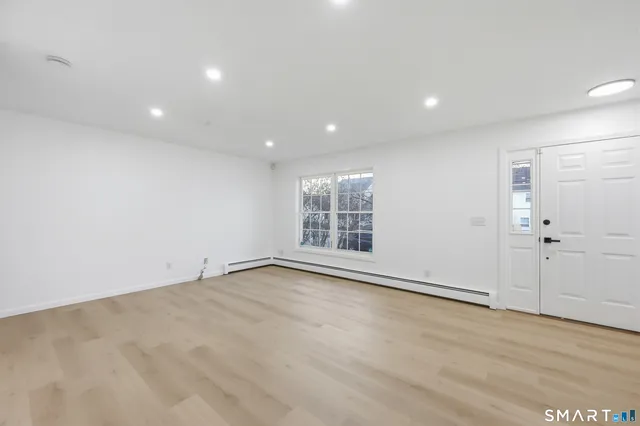 a view of an empty room with wooden floor and staircase
