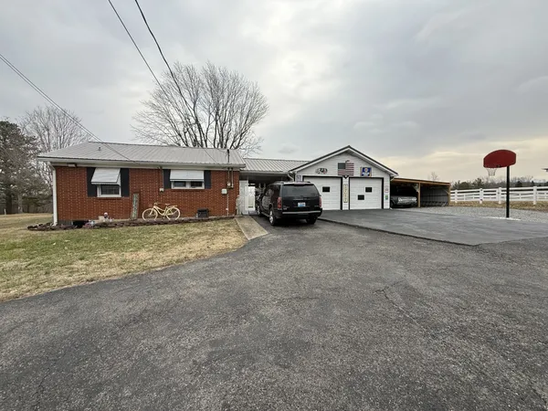 a view of a house with a yard and parking space