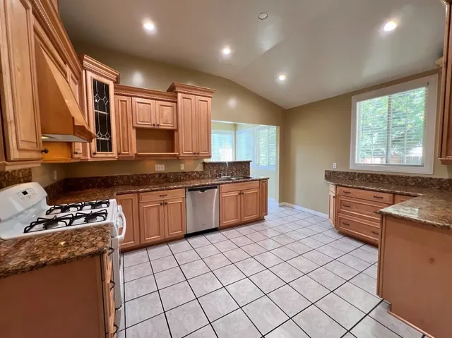 a kitchen with stainless steel appliances granite countertop a stove a sink and a microwave