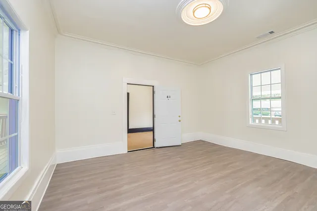 a view of empty room with wooden floor and fan