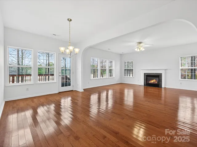 a view of an empty room with window and wooden floor