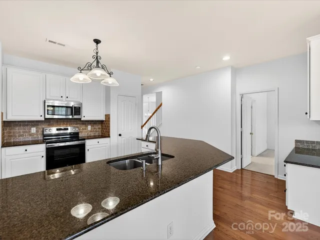 a kitchen with stainless steel appliances granite countertop a sink a stove and a refrigerator