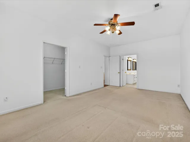 an empty room with fan chandelier fan and windows