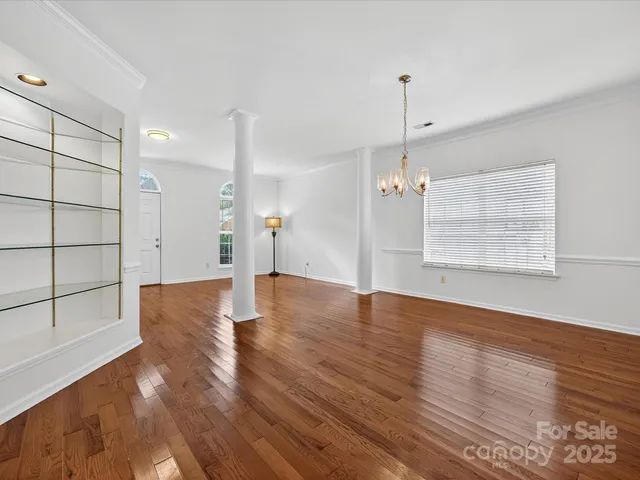 a view of an empty room with wooden floor windows and entryway