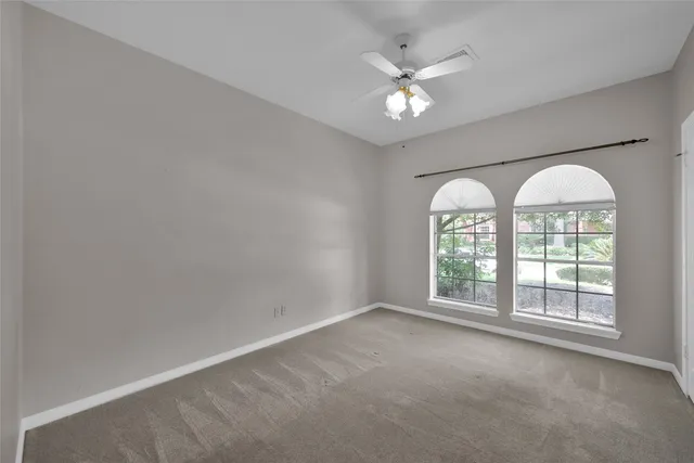 an empty room with windows and chandelier fan
