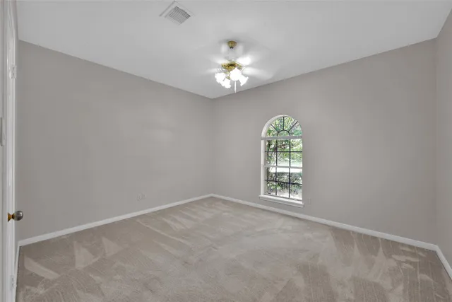 an empty room with windows and chandelier fan