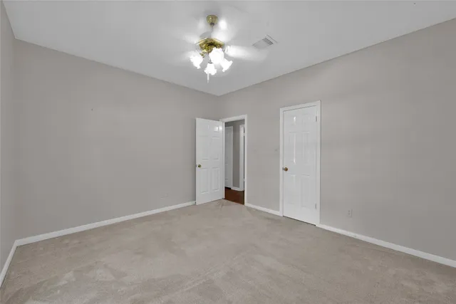 a view of an empty room with a chandelier fan