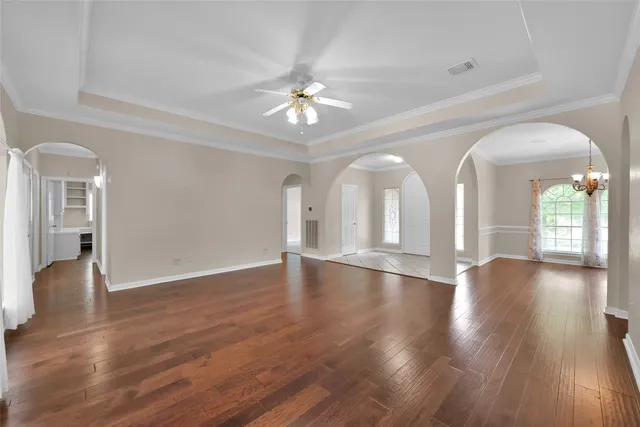 a view of an empty room with wooden floor and a kitchen