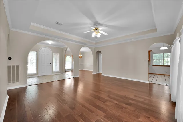 a view of empty room with wooden floor and fan