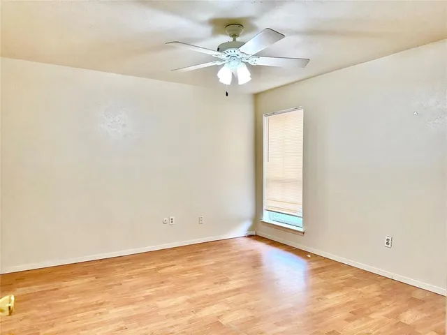 an empty room with a chandelier fan and windows