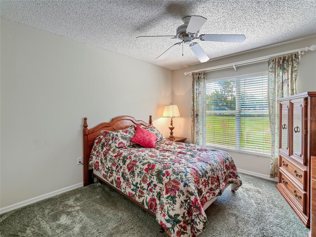 11228 Windrush Circle Hudson, FL 34667 - Photo 9 of 67 a bedroom with a bed a chandelier and a flat tv