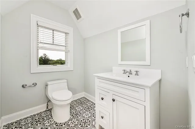 a bathroom with a toilet sink vanity and mirror