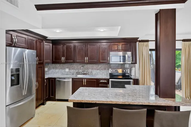 a kitchen with granite countertop kitchen island stainless steel appliances a refrigerator sink and stove