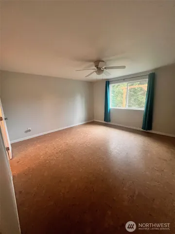 an empty room with windows and chandelier fan