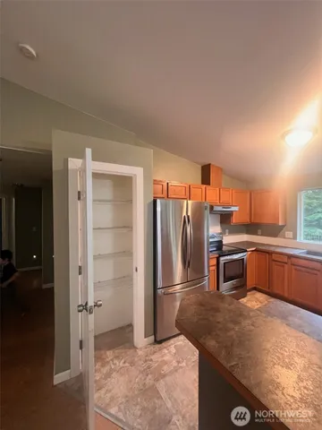 a kitchen with stainless steel appliances kitchen island granite countertop a refrigerator and a sink