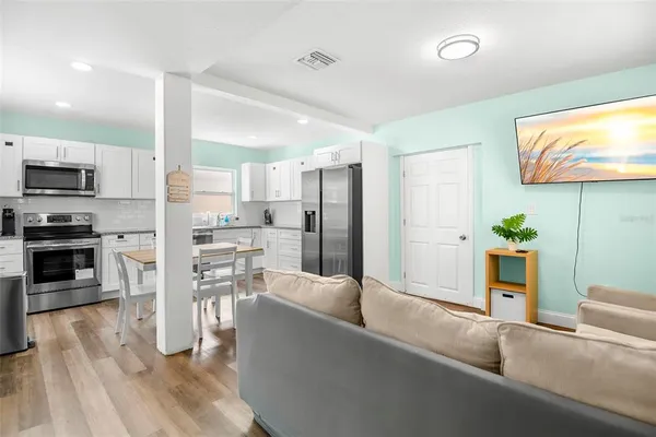 a living room with stainless steel appliances furniture a fireplace a flat screen tv and entryway
