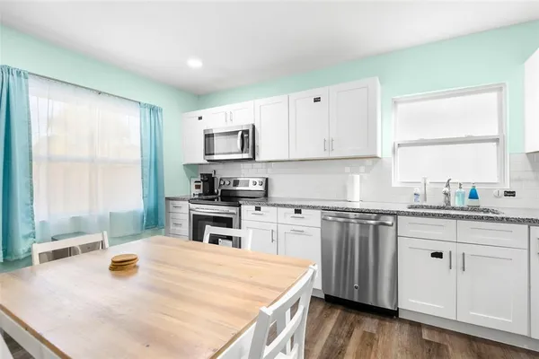 a kitchen with stainless steel appliances granite countertop a stove a sink and a white cabinets