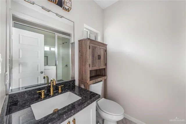 a bathroom with a granite countertop sink mirror vanity and toilet