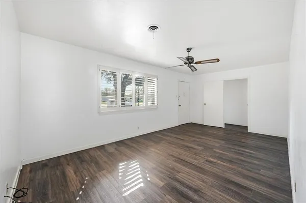 an empty room with wooden floor ceiling fan and windows