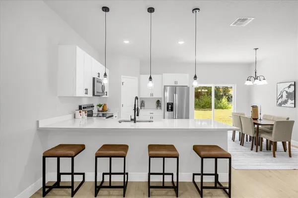 a kitchen with stainless steel appliances kitchen island granite countertop a table chairs and a sink