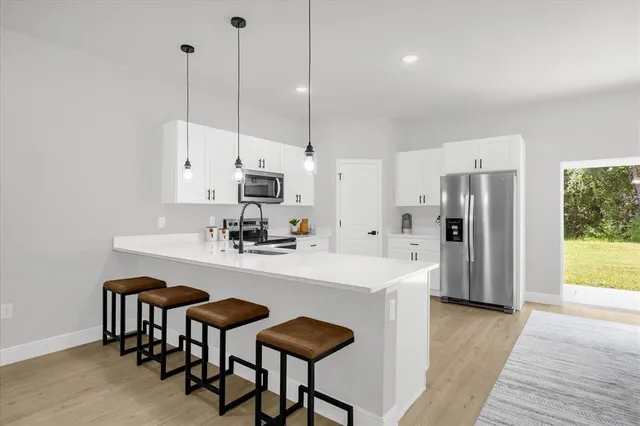 a kitchen with stainless steel appliances kitchen island a table chairs and a refrigerator
