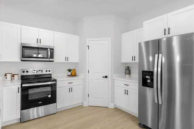 a kitchen with stainless steel appliances a refrigerator stove and white cabinets