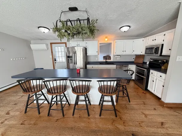 a kitchen with stainless steel appliances granite countertop a kitchen island a stove a table and chairs in it