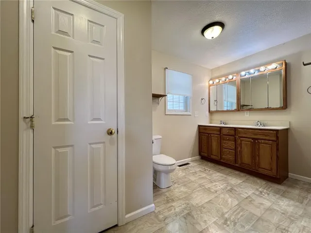 a bathroom with a granite countertop toilet sink and mirror