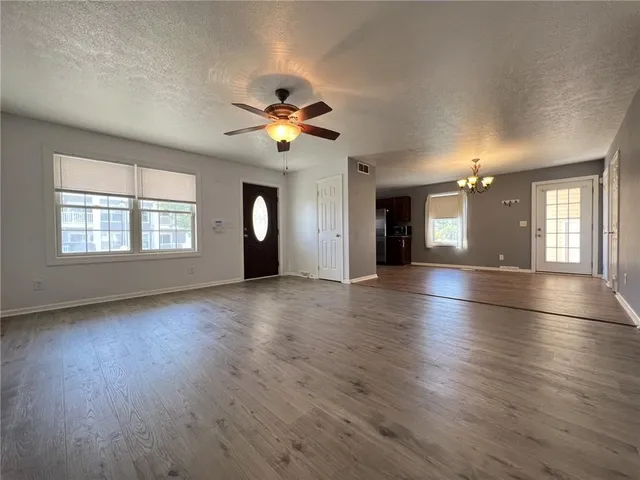 a view of an empty room with window and wooden floor