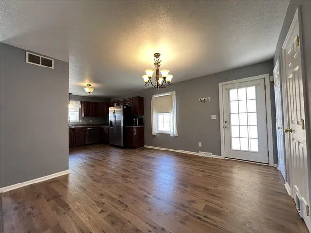 an empty room with wooden floor fireplace and windows