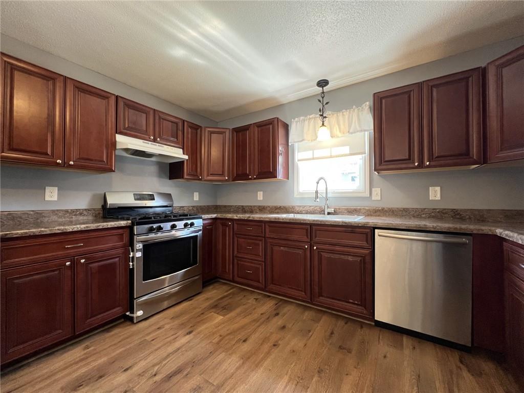 43 Maple Street Uniontown, PA 15401 - Photo 9 of 26 a kitchen with stainless steel appliances granite countertop wooden cabinets a stove a sink and dishwasher with wooden floor