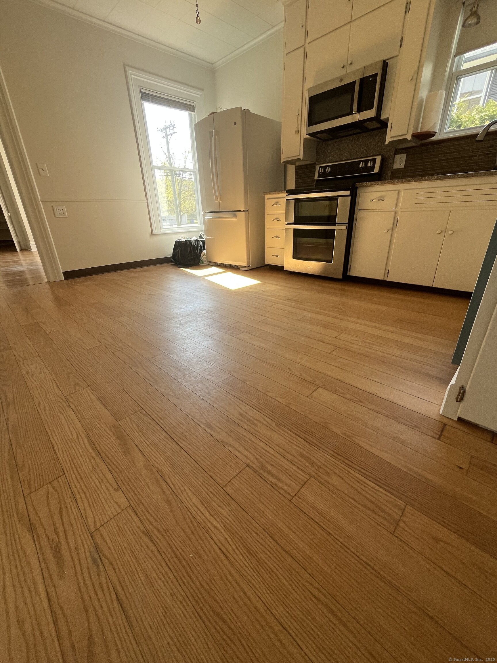 a view of a kitchen with wooden floor and electronic appliances