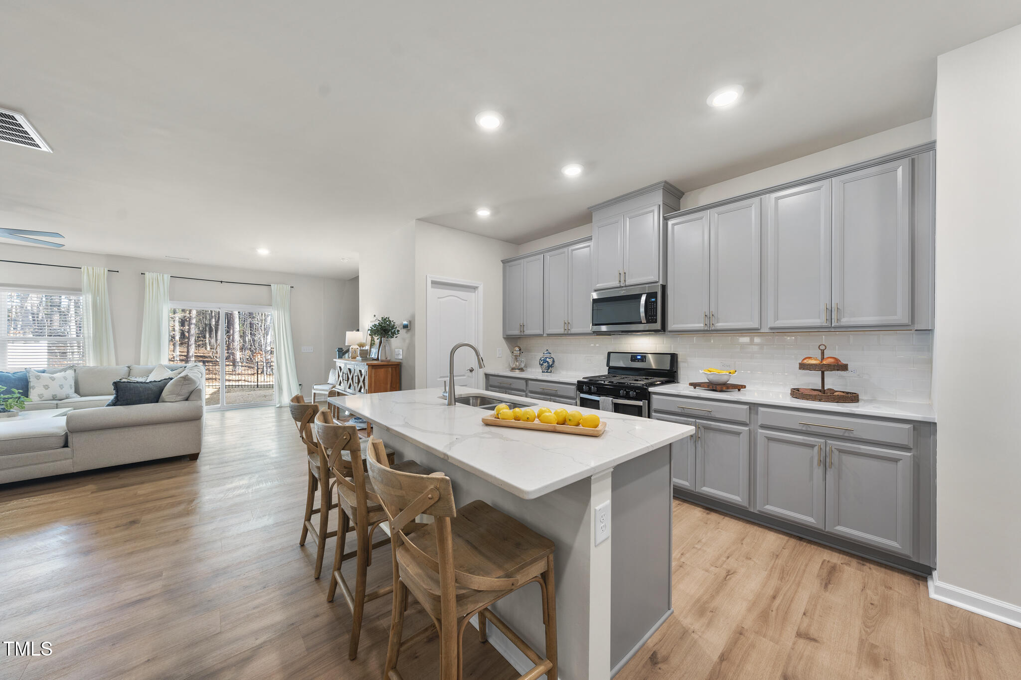 3408 Dropseed Drive Apex, NC 27502 - Photo 12 of 27 a kitchen with stainless steel appliances a stove a sink a refrigerator white cabinets and wooden floor