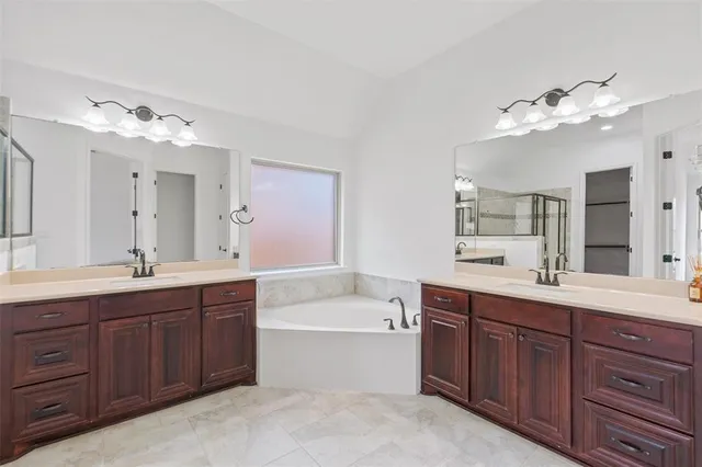 a bathroom with a tub a sink double vanity and mirror