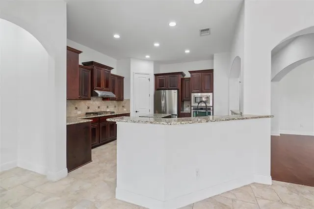 a kitchen with kitchen island stainless steel appliances a sink a stove a microwave a sink and a refrigerator