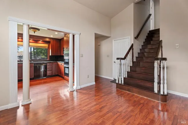 a view of a hallway with wooden floor staircase and a kitchen