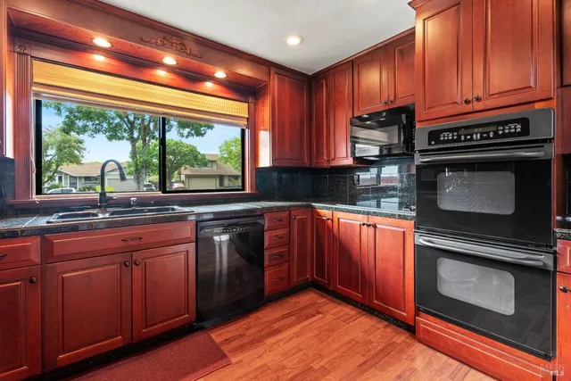 a kitchen with granite countertop wooden cabinets stainless steel appliances and a large window