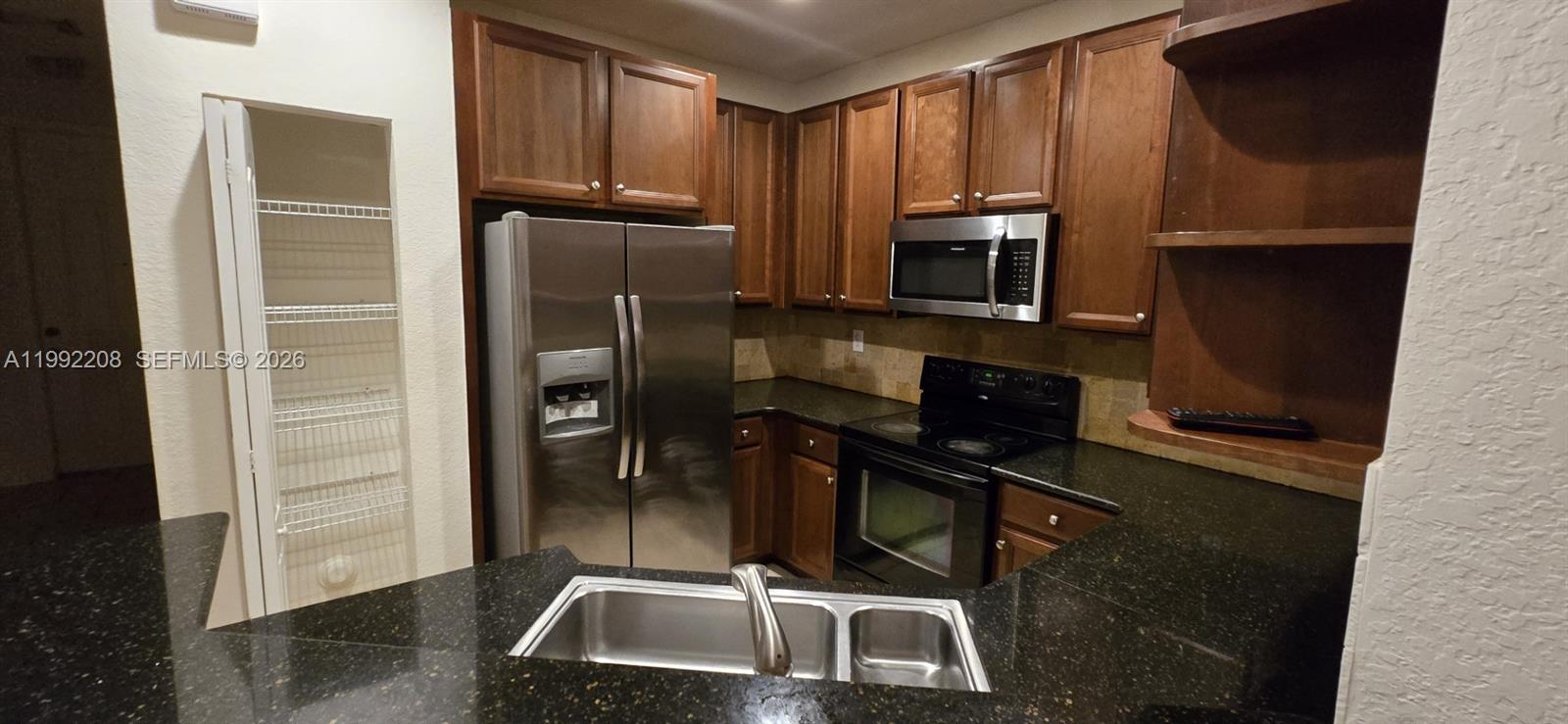 14067 Southwest 272nd Street Homestead, FL 33032 - Photo 26 of 36 a kitchen with a refrigerator a microwave a sink and cabinets