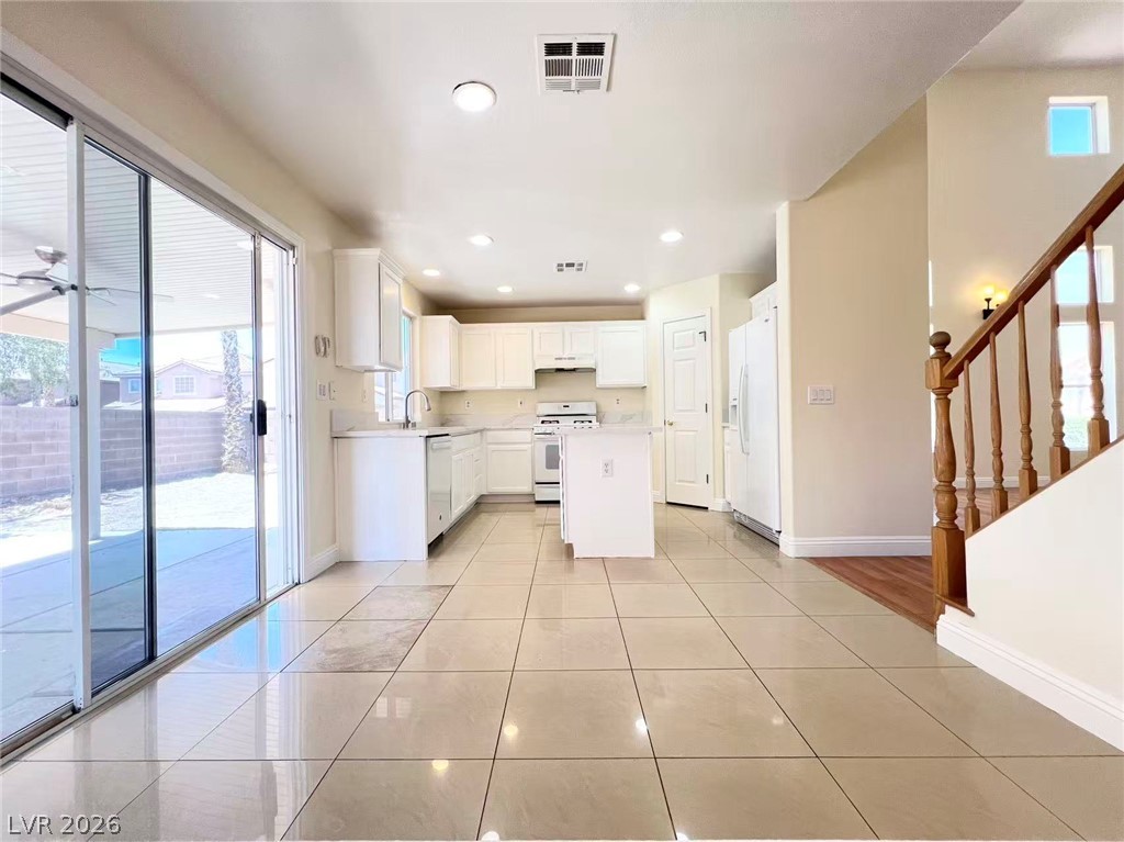 9891 Ridge Hill Avenue Las Vegas, NV 89147 - Photo 8 of 29 Bright, open-concept kitchen with white cabinetry and an inviting view to the backyard.